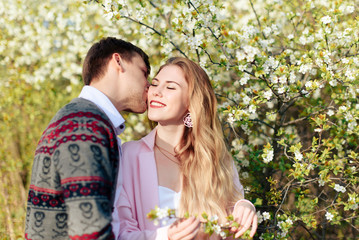 Fototapeta premium a young couple in love cuddles against the background of blooming spring cherry orchards 1