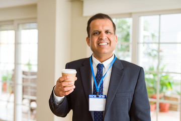 Middle age business man drinking a cup of coffee wearing identification card