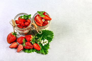 dessert in jar with yoghurt and strawberry, biscuit cake and cream cheese on over light gray background. Copy space