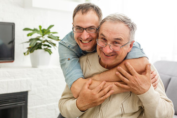 The old man on a wheelchair and his son . A man hugs his elderly father. They are happy and smiling