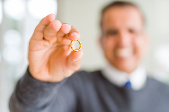 Close up of middle age man holding a engagement ring and smiling to the camera