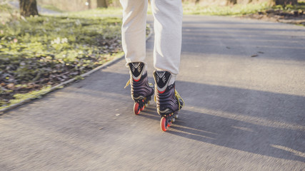  Quick movement of inline boots on the road at sunset. Outdoor inline skating on a trail beside the...