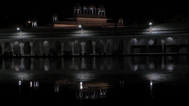 Night time reflected view of Gurdwara Bangla Sahib, one of the most prominent Sikh gurdwara in India, in the holy pond. Pilgrims and tourists seeking peace and calm 