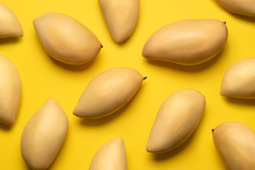 Several fresh mango fruits on a yellow background.