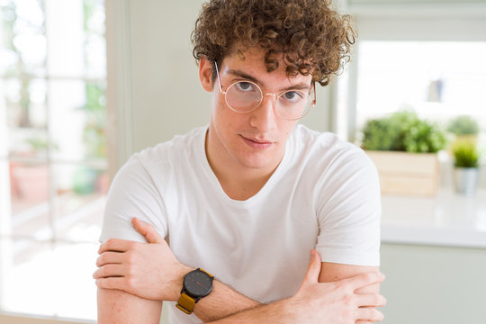Young handsome man wearing glasses Relaxed with serious expression on face. Simple and natural with crossed arms