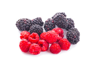 pile of raspberries and blackberries with leaves isolated on white background