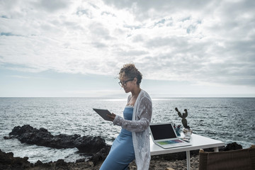 Young happy businesswoman  working outdoor in alternative office enjoying the nature and the ocean...