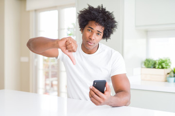 African American man using smartphone with angry face, negative sign showing dislike with thumbs...