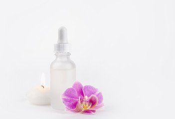 Blank luxurious white matte cosmetic dropper bottle with blank empty label for cosmetic medical products ad background concept. Studio shot, with pink glamorous orchid blossom and candle burning.