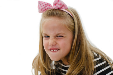 Close up of a portrait little girl shows her furrowed brow and irritated frown. Isolated on white background