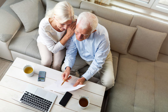 Older couple reading papers together on sofa