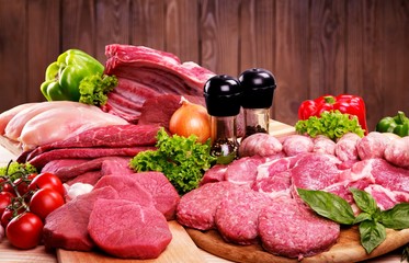 Fresh raw meat background with vegetables on wooden desk isolated on white background
