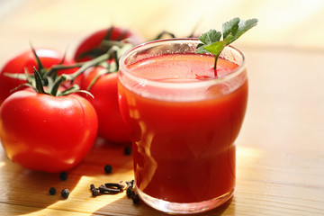  Tomato juice in a glass Cup with a bunch of ripe tomatoes, on a light wood background. Close up.