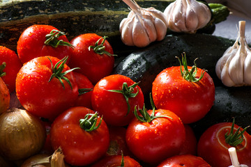 Ripe fresh harvested vegetables on table. Onions, tomatoes, garlic, pepper, zucchini in kitchen. Making delicious vegetarian meal or canning veggies for winter in jars. Concept of healthy eating