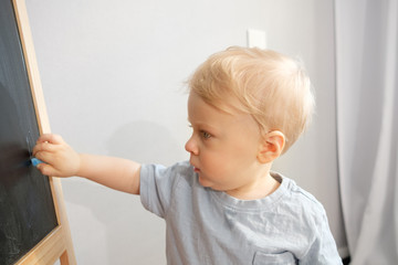 Child draws with crayons at home on the blackboard