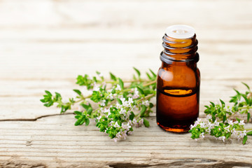 thyme essential oil and thyme flowers on the wooden board