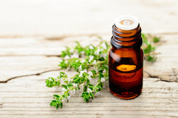 thyme essential oil and thyme flowers on the wooden board