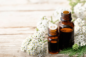 yarrow essential oil and fresh yarrow flowers on the wooden board
