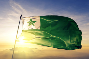 Esperanto flag waving on the top sunrise mist fog