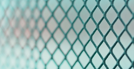 Fototapeta premium metal grid with square cells in perspective on a light background, blurred image