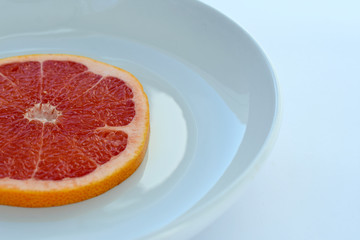 Fototapeta na wymiar grapefruit slice on a plate fragment