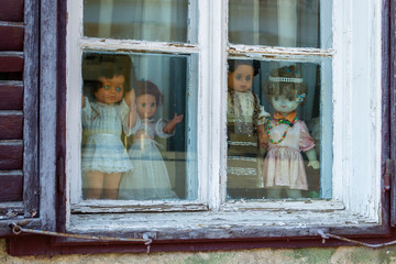 Four creepy dolls dressed in white and with traditional Romanian clothes, displayed in a window,...