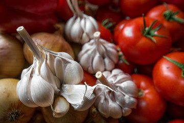 Ripe, fresh, harvested vegetables on table. Onions, tomatoes, garlic on kitchen table prepared to make a delicious vegetarian meal or for canning veggies for winter in jars. Concept of healthy eating