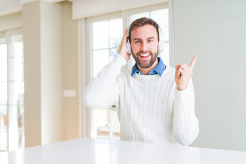 Handsome man wearing headphones and listening to music very happy pointing with hand and finger to the side