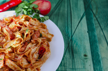 spicy spaghetti with tomato paste on a white plate green wooden background copy space