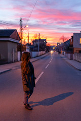 Obraz premium Girl looking down the road at sunset 
