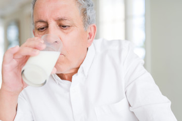 Handsome senior man drinking a glass of fresh milk in the morning