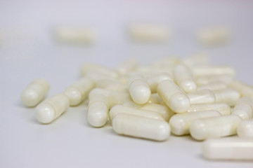 Pile of capsules with vitamin powder inside, on white background