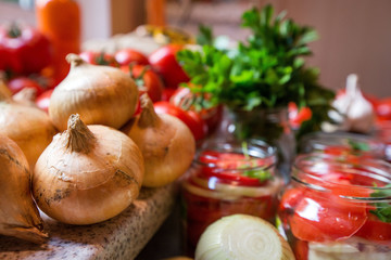 Canning fresh tomatoes with onions in jelly marinade. Woman hands putting red ripe tomato slices and onion rings in jars. Basil, parsley leaves on top of onions. Vegetable salads for winter