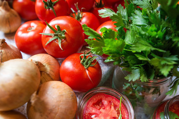 Canning fresh tomatoes with onions in jelly marinade. Woman hands putting red ripe tomato slices and onion rings in jars. Basil, parsley leaves on top of onions. Vegetable salads for winter