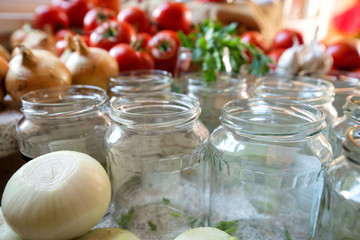 Canning fresh tomatoes with onions in jelly marinade. Woman hands putting red ripe tomato slices and onion rings in jars. Basil, parsley leaves on top of onions. Vegetable salads for winter