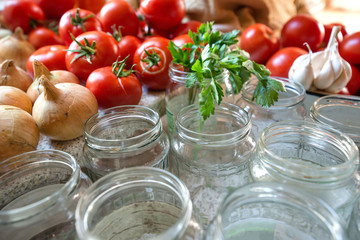 Canning fresh tomatoes with onions in jelly marinade. Woman hands putting red ripe tomato slices and onion rings in jars. Basil, parsley leaves on top of onions. Vegetable salads for winter