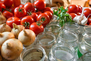 Canning fresh tomatoes with onions in jelly marinade. Woman hands putting red ripe tomato slices and onion rings in jars. Basil, parsley leaves on top of onions. Vegetable salads for winter