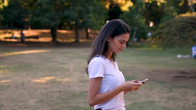 Pretty girl texting on the phone in park