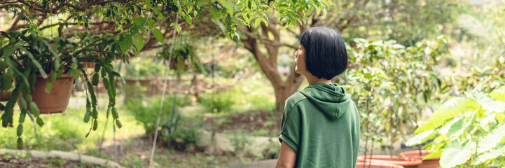 portrait of Asian mature woman stand at the fruit farm, banner of travel and technology concept