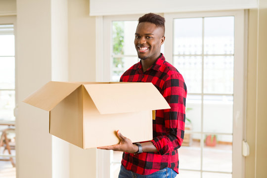 Young african american man holding a carton box, packing cardboard delivery package at home
