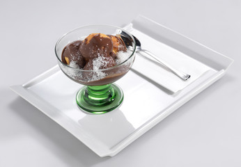Profiterole with on a white plate with a spoon.