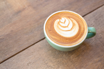 atte hot coffee in a green cup with latte art and roasted coffee on wooden table background