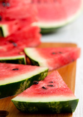A lot of slices of ripe juicy watermelon on bamboo board, side view. Selective focus.