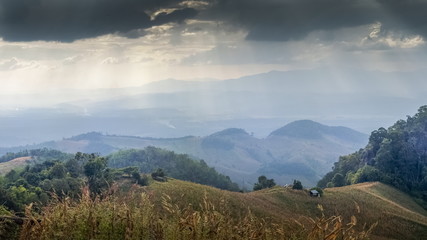 Mountain view evening of dark clouds moving with sun rays above the hills, sunset with soft rain at Doi Samur Dao , Srinan National Park, Nan, Thailand.
