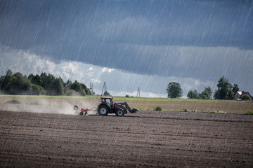 Agricultural background with tractor pulling plow, throwing dust in air. Combine harvester at wheat...