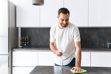 Attractive young man cleaning kitchen