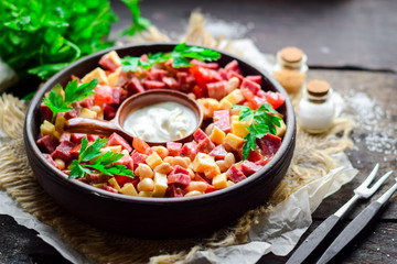 Vegetable salad from beet, red sweet pepper, carrots, beans and smoked sausage with sour cream.