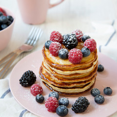 Homemade pancakes with raspberry, blackberry ,blueberry on white wooden background, side view. Close-up.