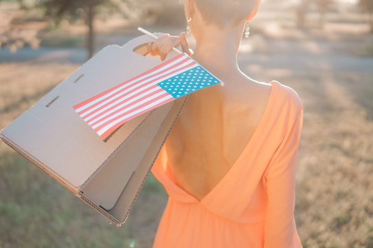 Memorial day sale, Independence day sale. Female hand with paper bag and american flag in spring or summer park - Powered by Adobe