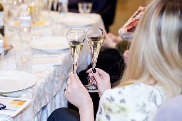 girl holding two glasses with champagne sitting in a restaurant